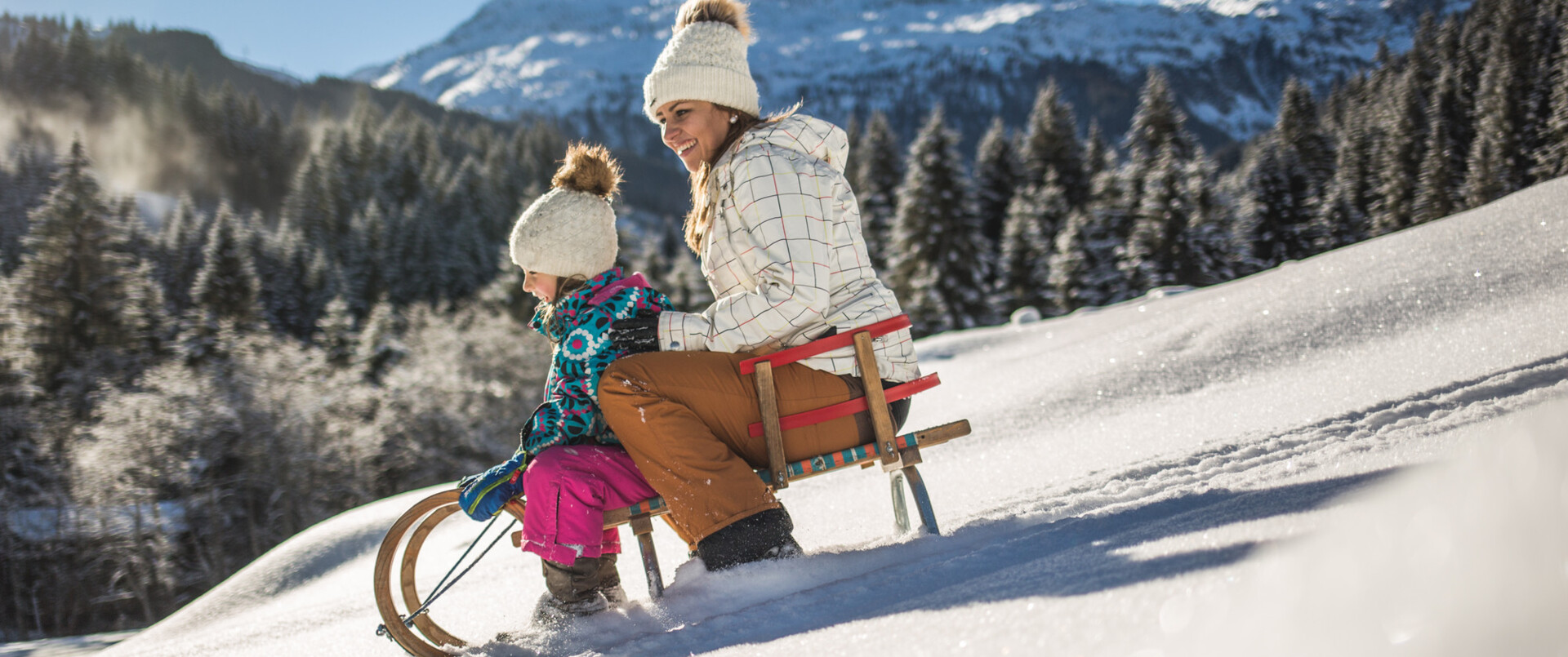 Mutter und Kind beim Schlitten fahren im Winterurlaub im Hotel Diellehen in Großarl.