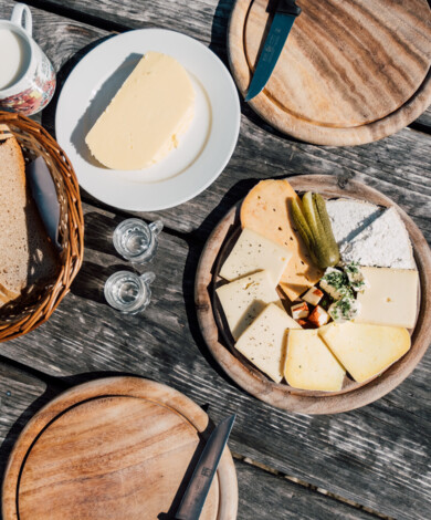 Blick auf eine typische Käsejause mit Schnittkäse, frischer Bauernbutter und einem Glas Milch.