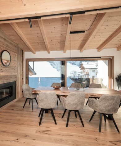 Loft Appartement - großzügiger Essbereich mit großem Holztisch und modernen Polstersesseln vor dem offenen Kamin.