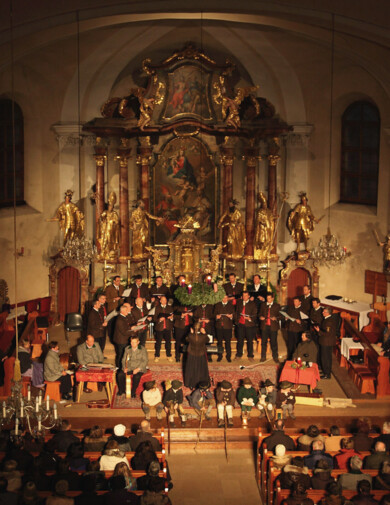 Blick auf die Sängerinnen und Sänger beim Großarler Adventsingen, welche vor dem Altar der Pfarrkirche stehen.