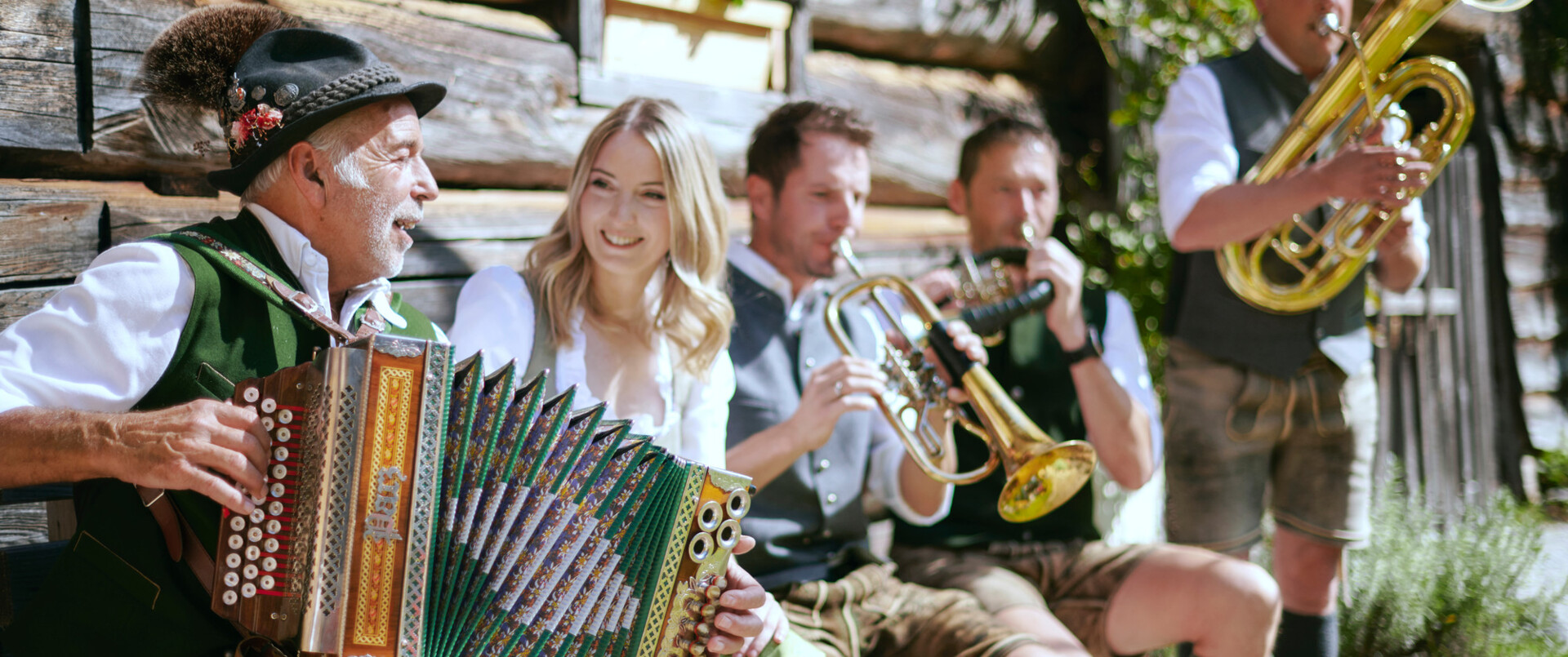 Musikanten in Tracht spielen ihre Instrumente vor einer Berghütte