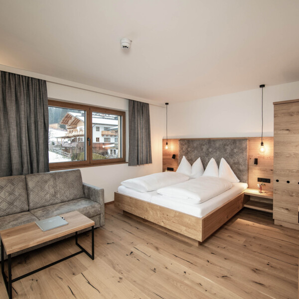 Moderne und großzügige Zimmer mit viel Holz und grauen Akzenten.