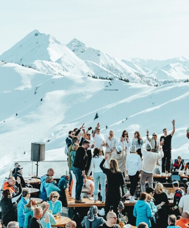Junge Leute feiern im neuen Großarler Bergrestaurant "Skylounge Wolke 7" mit Blick auf die tiefverschneite Berglandschaft.