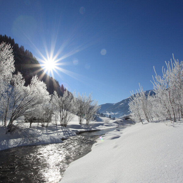 Tief verschneite Winterlandschaft mit Bach im Großarltal, Salzburger Land.