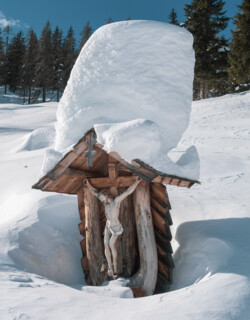 Verschneites Kreuz in der tief verschneiten Landschaft von Großarl, Salzburger Land.