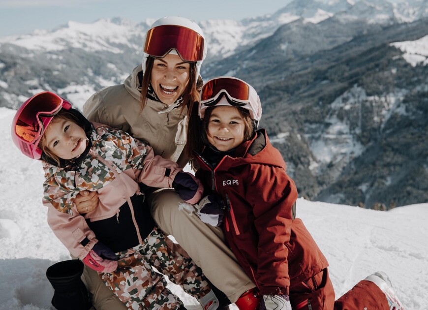 Eine Mutter sitzt mit ihren zwei Mädchen im Schnee und hat Spaß winterlichen Landschaft in Großarl.