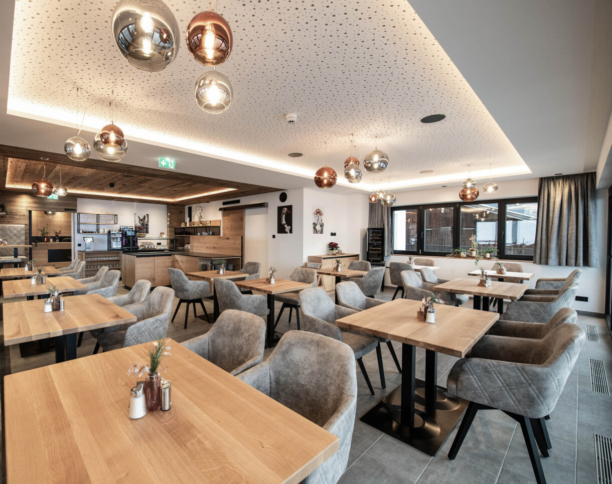 Frühstücksraum mit modernen Holztischen und gemütlichen Polsterstühlen.