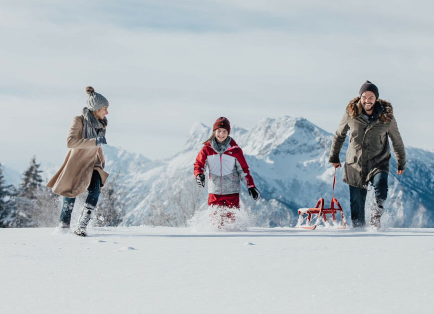 Familie mit Schlitten im Tiefschnee - Rodeln im Familienurlaub in Großarl.