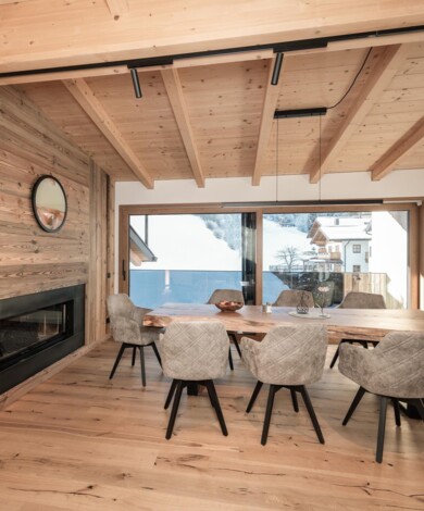 Loft Appartement - großzügiger Essbereich mit großem Holztisch und modernen Polstersesseln vor dem offenen Kamin.