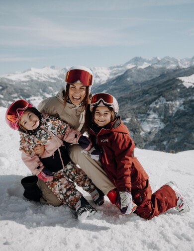 Eine Mutter sitzt mit ihren zwei Mädchen im Schnee und hat Spaß winterlichen Landschaft in Großarl.