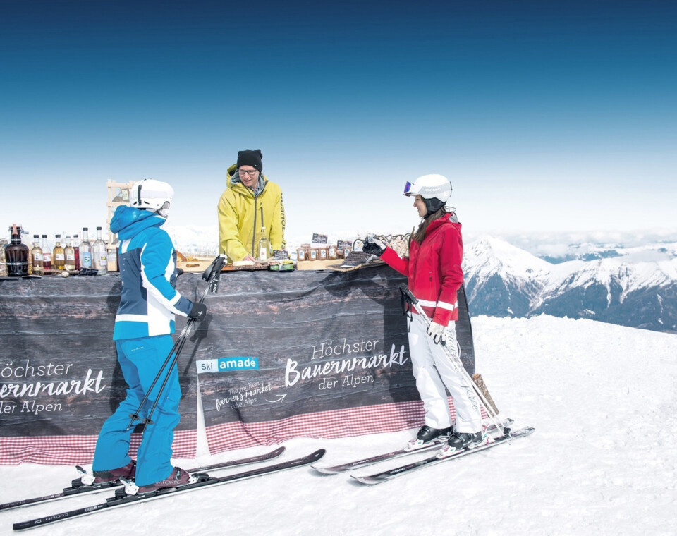 Zwei Skifahrerinnen am höchsten Bauernmarkt der Alpen während der Wein- & Genusswoche in Großarl.