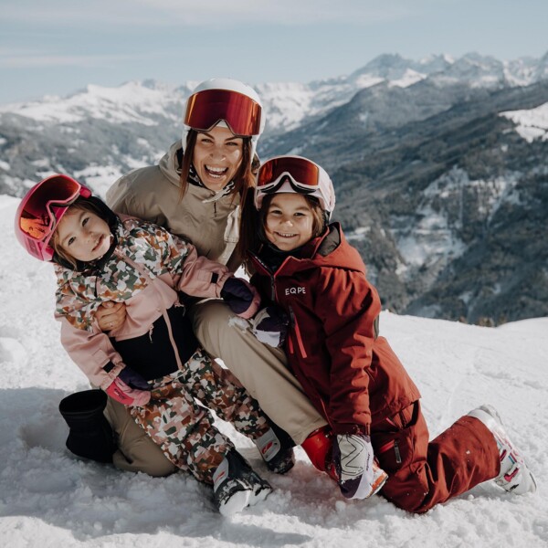 Eine Mutter sitzt mit ihren zwei Mädchen im Schnee und hat Spaß winterlichen Landschaft in Großarl.