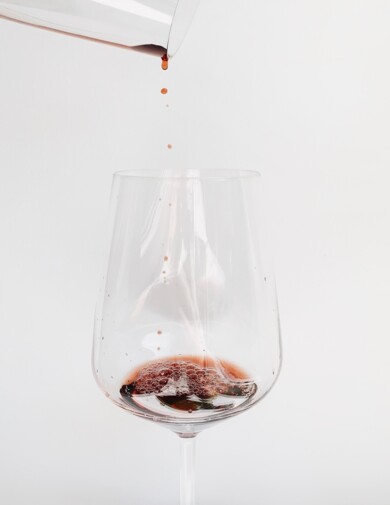 Rotwein wird in ein Glas eingeschenkt.